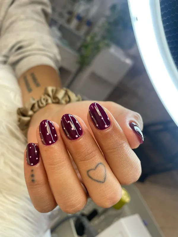 Uñas en color ciruela con puntitos blancos
