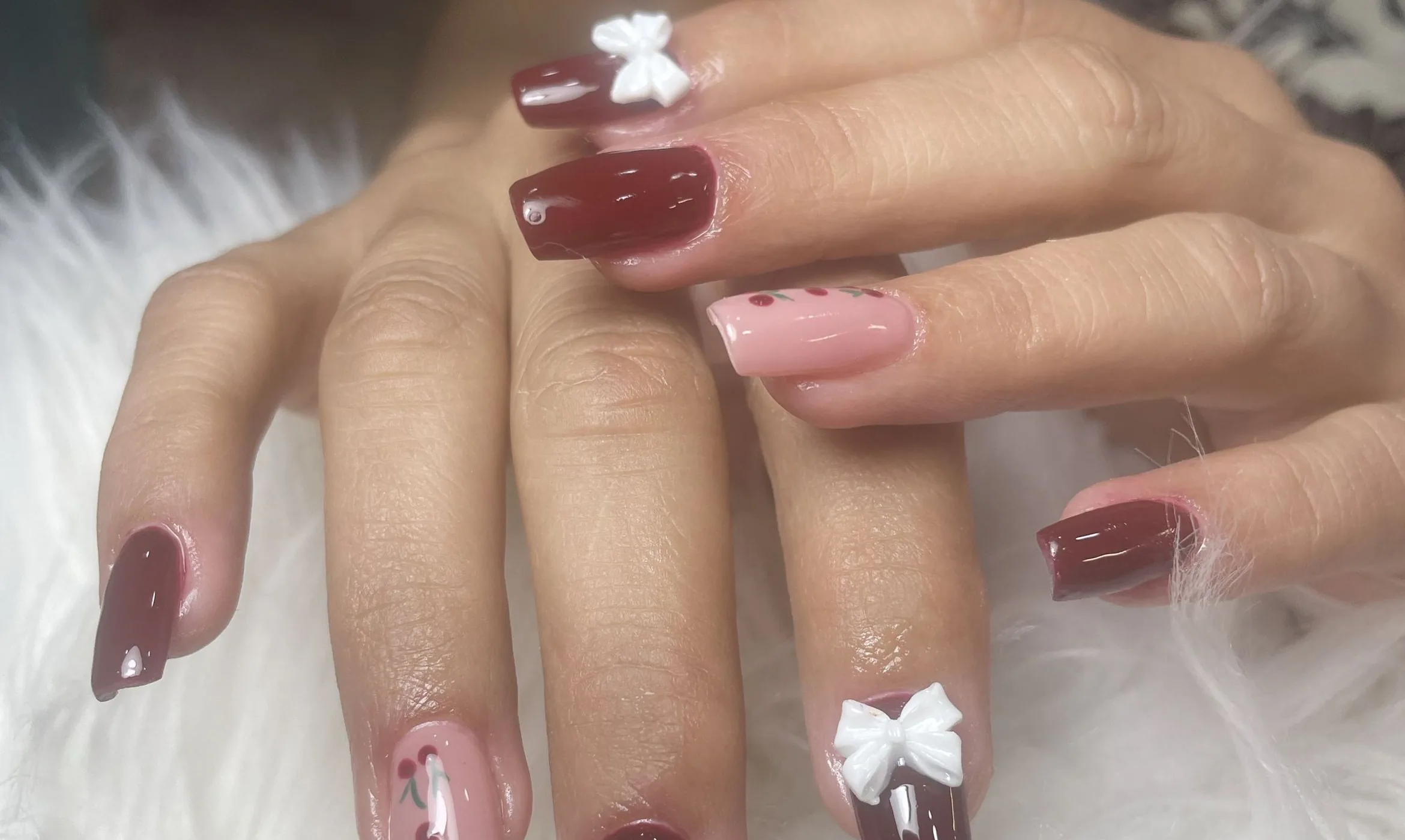 Extensiones de uñas en burdeos y nude con lazos 3D, hechas en Vivi Nails Studio, Córdoba